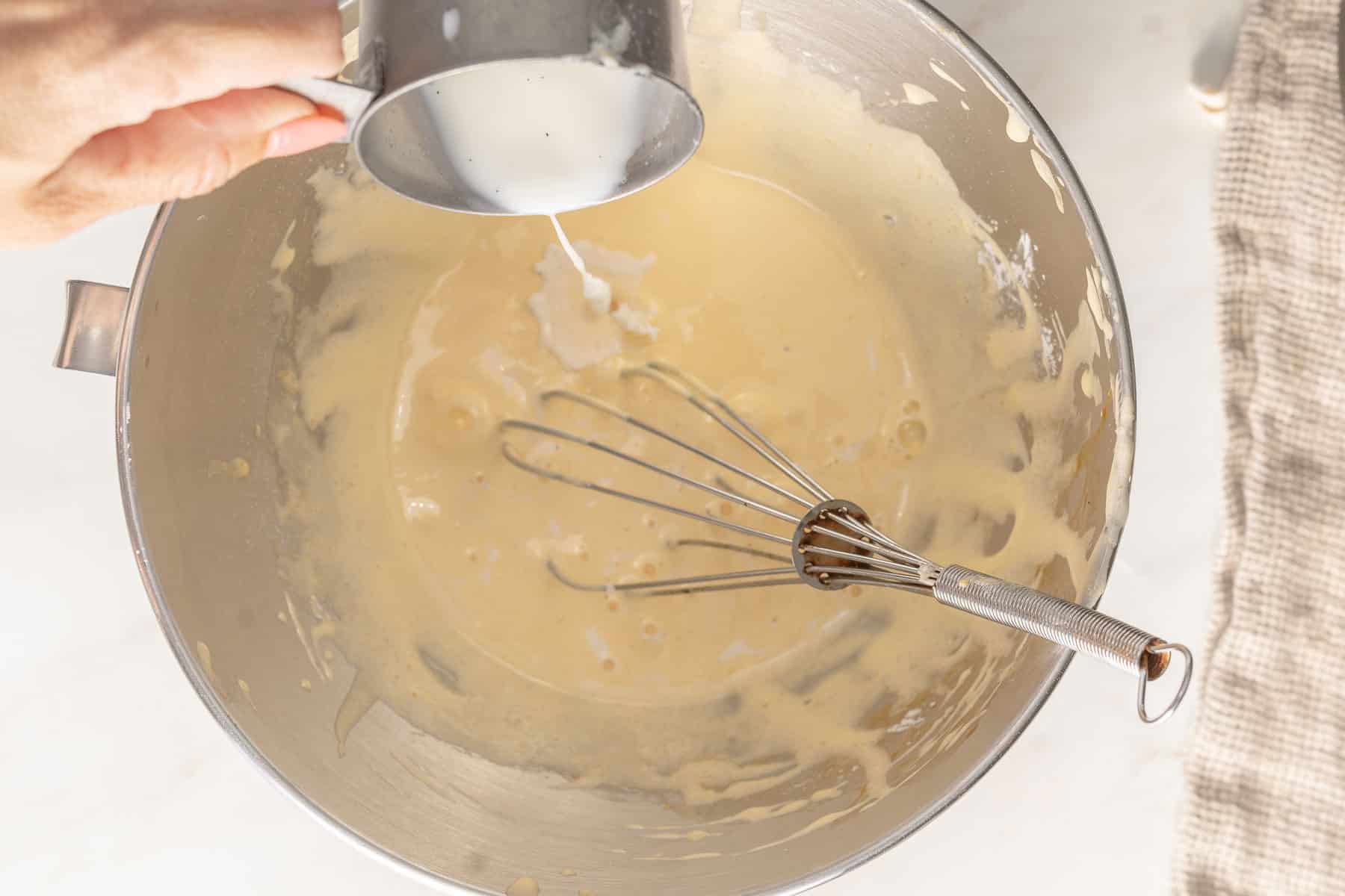 Tempering eggs by adding warm milk.