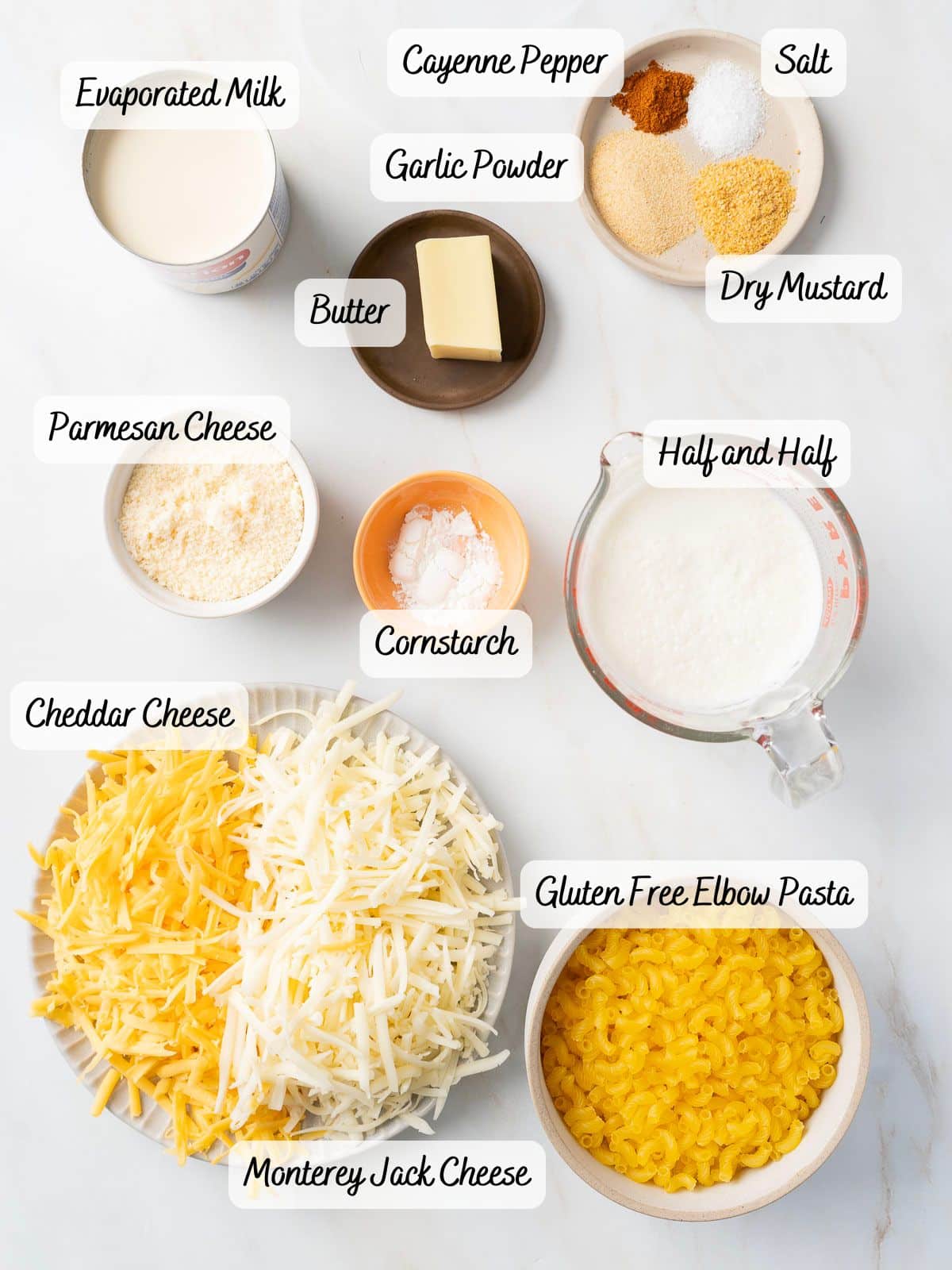 Ingredients for mac and cheese including evaporated milk, cornstarch, cayenne pepper, garlic powder, dry mustard, salt, butter, half and half, cheddar, Monterey Jack, Parmesan, and gluten-free pasta.