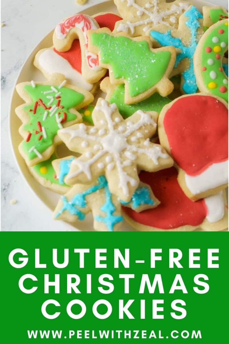 A plate of colorful, decorated gluten-free Christmas cookies, including snowflakes, trees, and Santa hats, with a website URL displayed at the bottom.