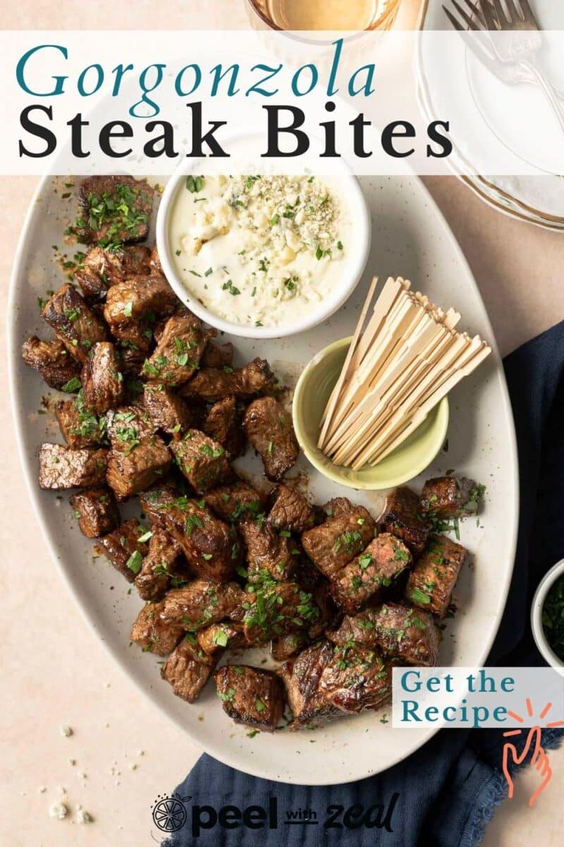 A plate of gorgonzola steak bites with a bowl of sauce and skewers, garnished with herbs. A card reads "Get the Recipe.