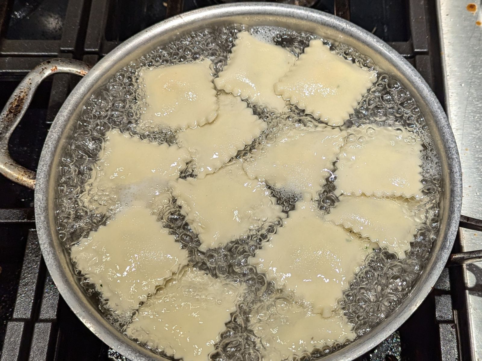Gluten-free ravioli boils in a metal pot filled with bubbling water on the stove.