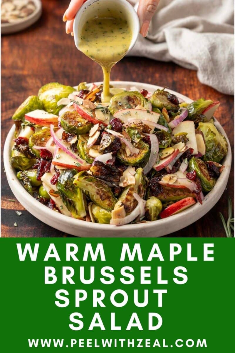Plate of warm maple Brussels sprout salad with sliced onions, apples, almonds, and a hand pouring dressing over it. Text reads "Warm Maple Brussels Sprout Salad" and website URL is shown.