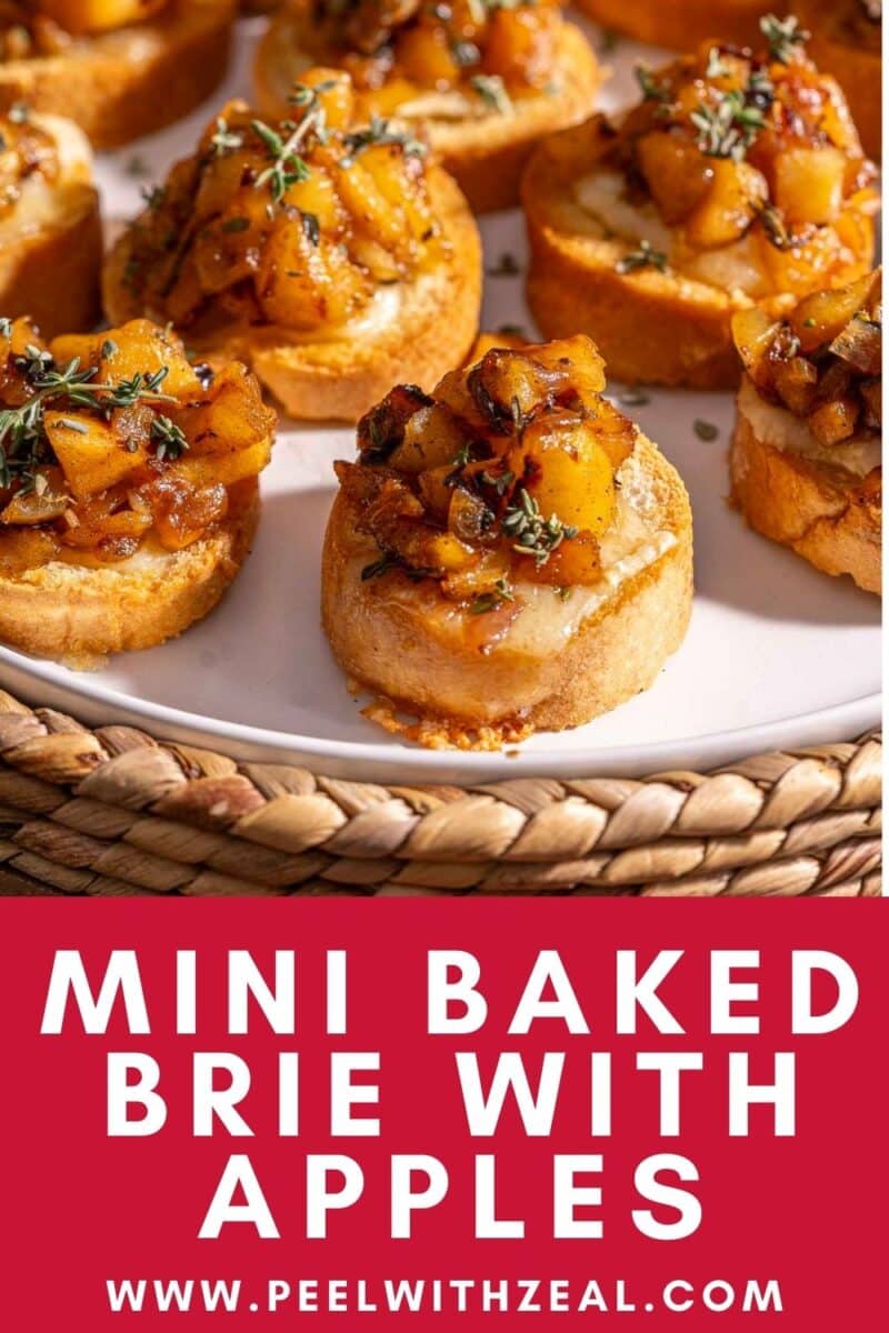 Mini baked brie with caramelized apples on toast, garnished with herbs, displayed on a white plate.