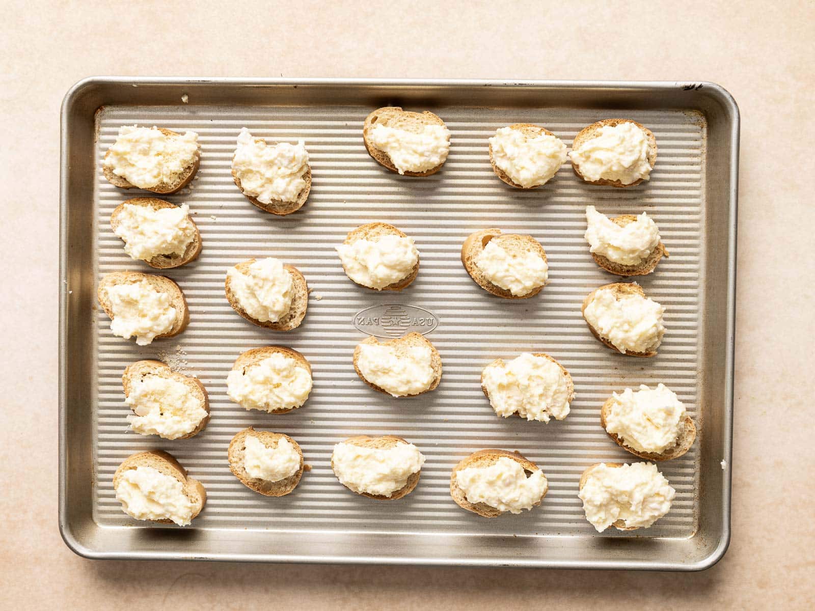 Slices of bread topped with a creamy mixture are arranged on a baking sheet, creating a delicious template for your next culinary feast.