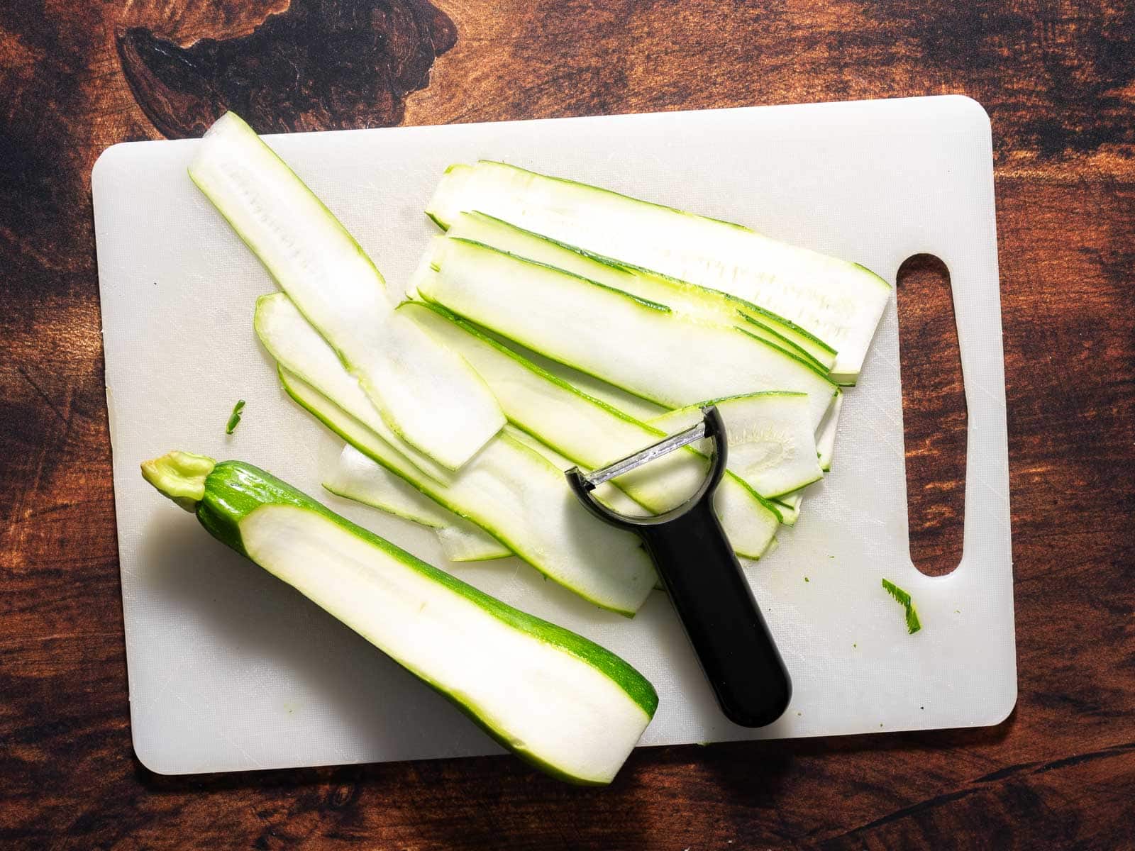 Cutting thin strips of zucchini with a peeler. 