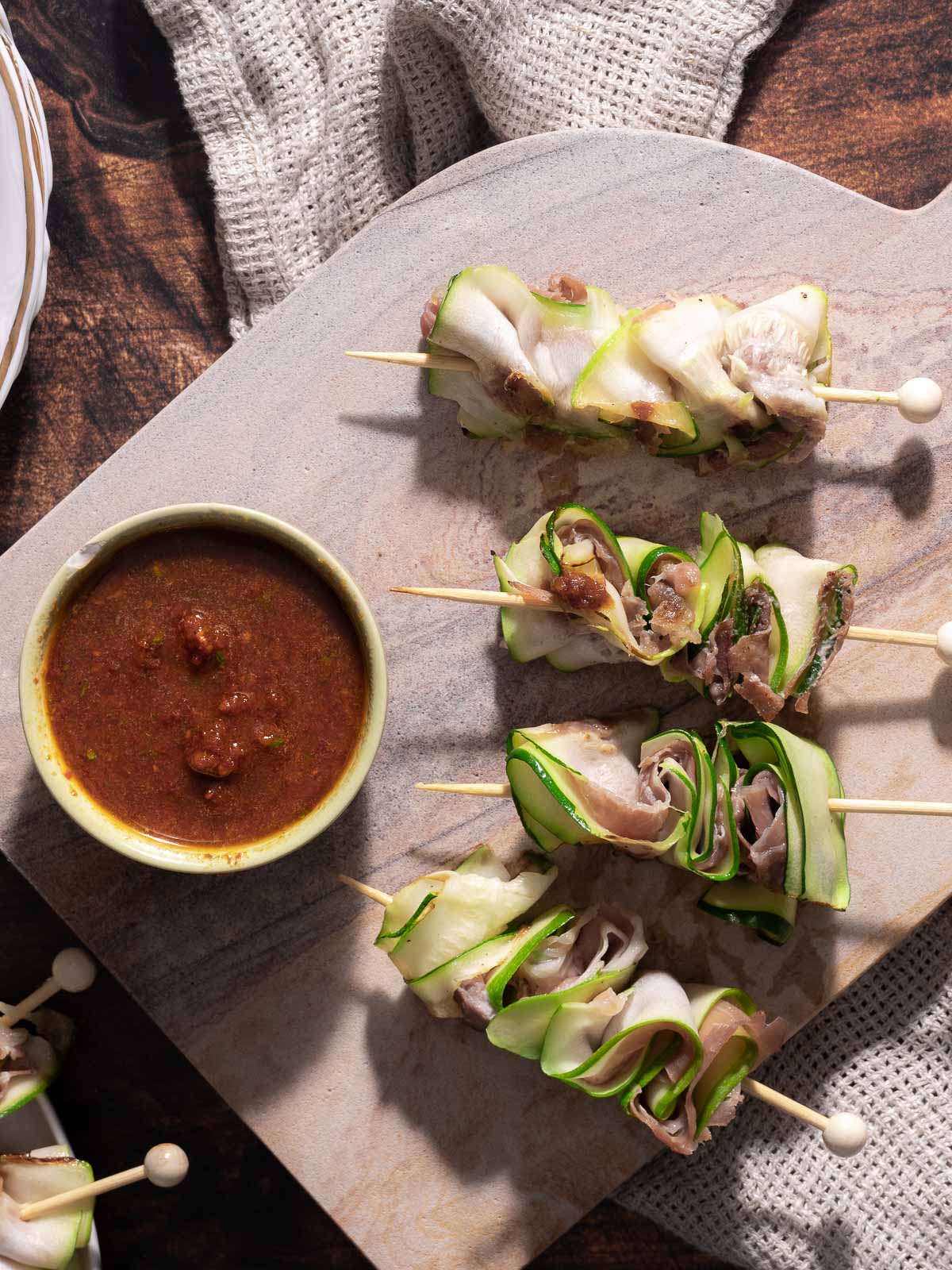 Skewers of zucchini slices make the perfect zucchini appetizer, elegantly arranged on a board, served with a bowl of dipping sauce.
