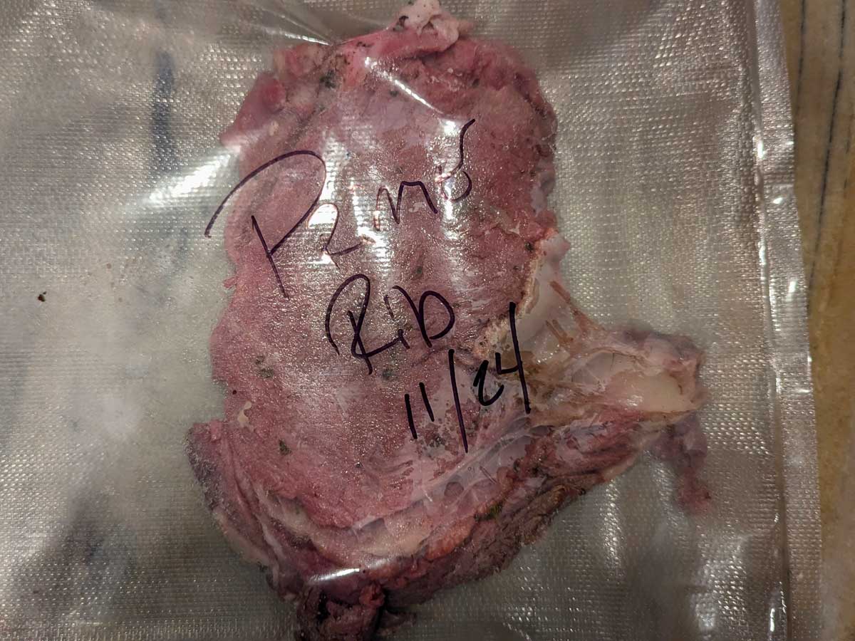 A vacuum-sealed piece of meat labeled with handwritten text "Sous Vide Prime Rib 11/14" on the packaging.