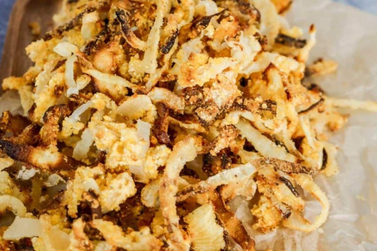 A pile of crispy, golden-brown fried onions on parchment paper adds the perfect touch to your gluten-free Thanksgiving recipes.
