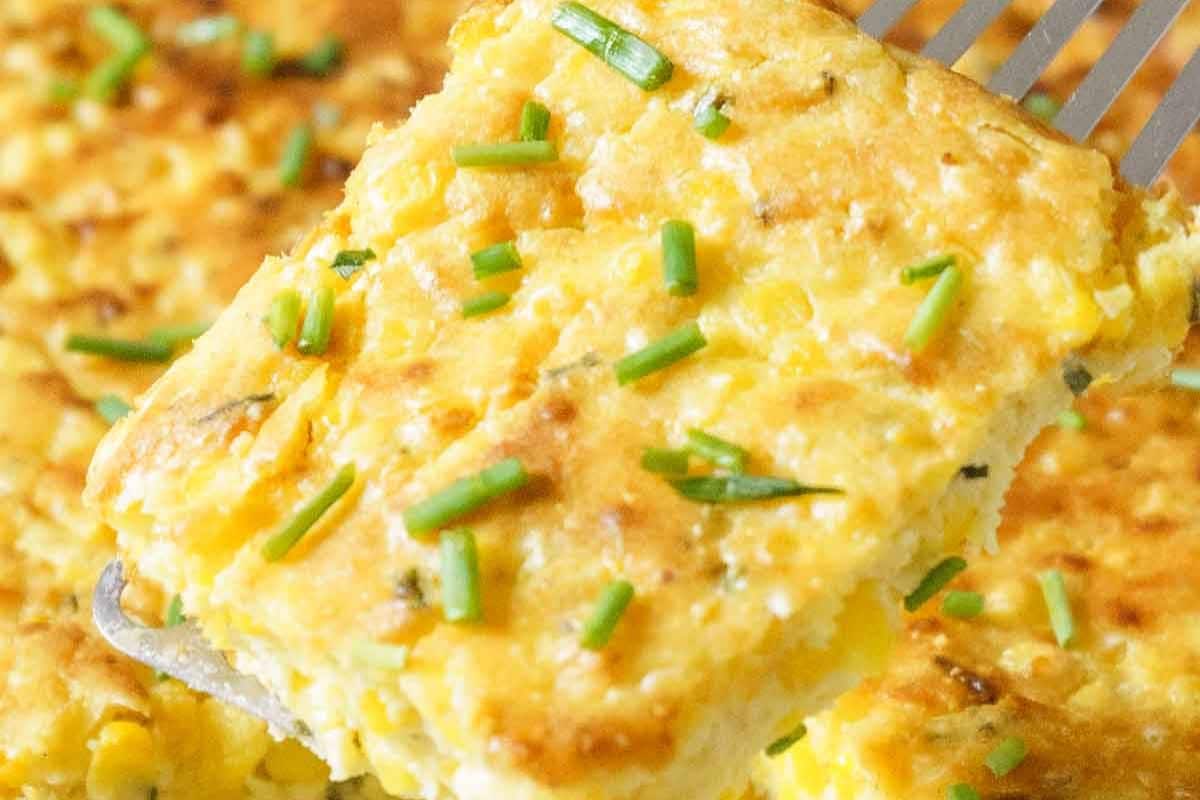 A close-up of a fork holding a piece of baked egg dish topped with chopped chives, perfect for your Thanksgiving table, offering a delightful gluten-free option.