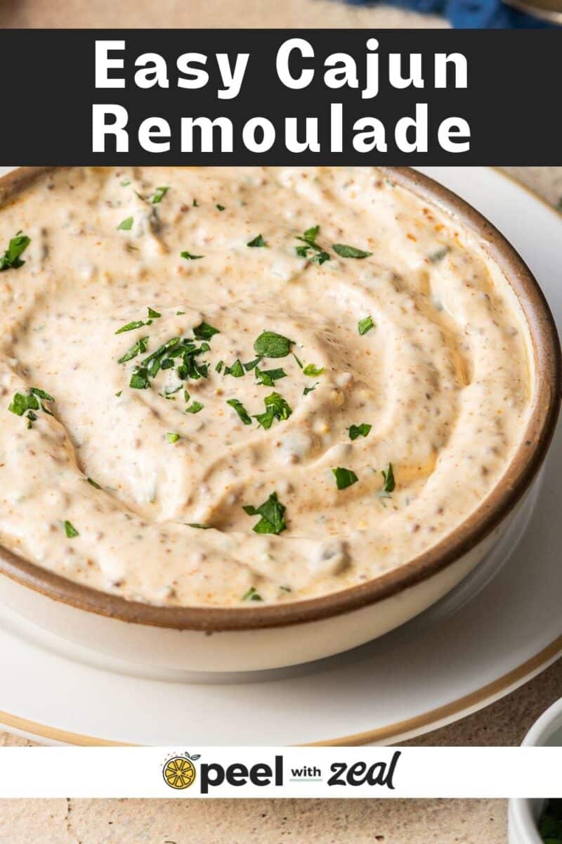 Bowl of creamy Cajun remoulade garnished with chopped herbs.