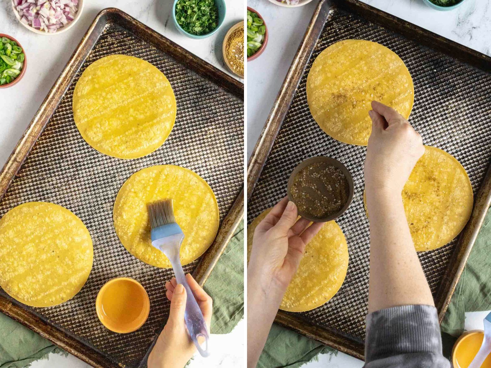Two corn tortillas on a baking sheet being brushed with oil and sprinkled with seasoning. Ingredients are visible in small bowls around the sheet.