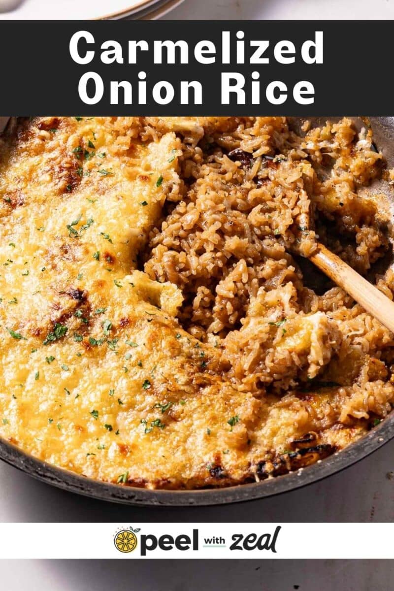 A skillet of caramelized onion rice with a golden crust on top and a wooden spoon, topped with herbs.