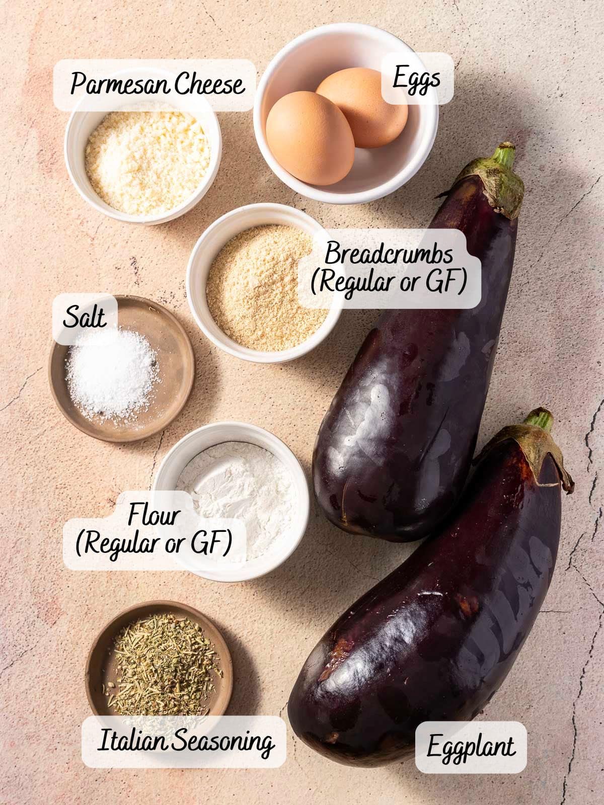Ingredients for a recipe: two eggplants, eggs, Parmesan cheese, breadcrumbs, salt, flour, and Italian seasoning, arranged on a light surface.