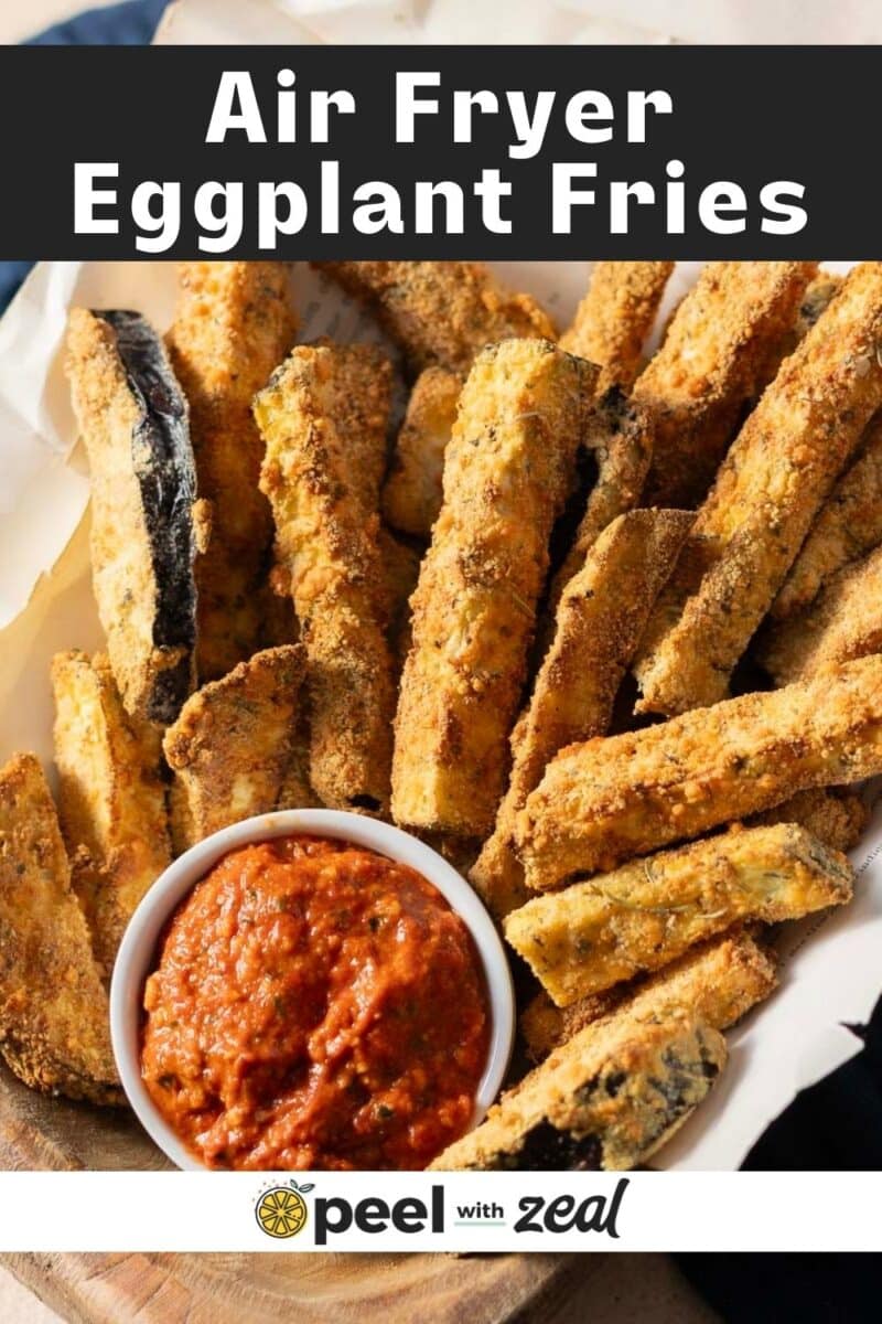 A plate of air fryer eggplant fries served with a bowl of red dipping sauce.