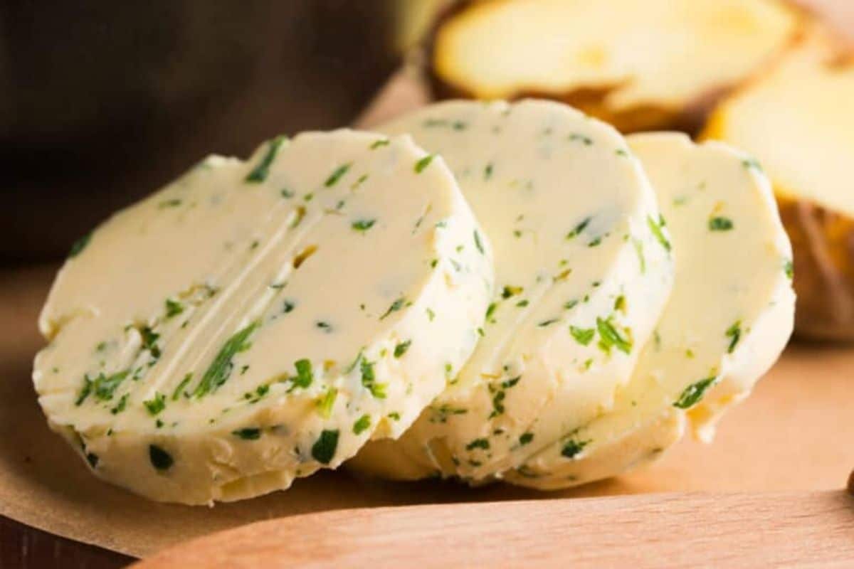 Three slices of herb-infused compound butter on a wooden surface.