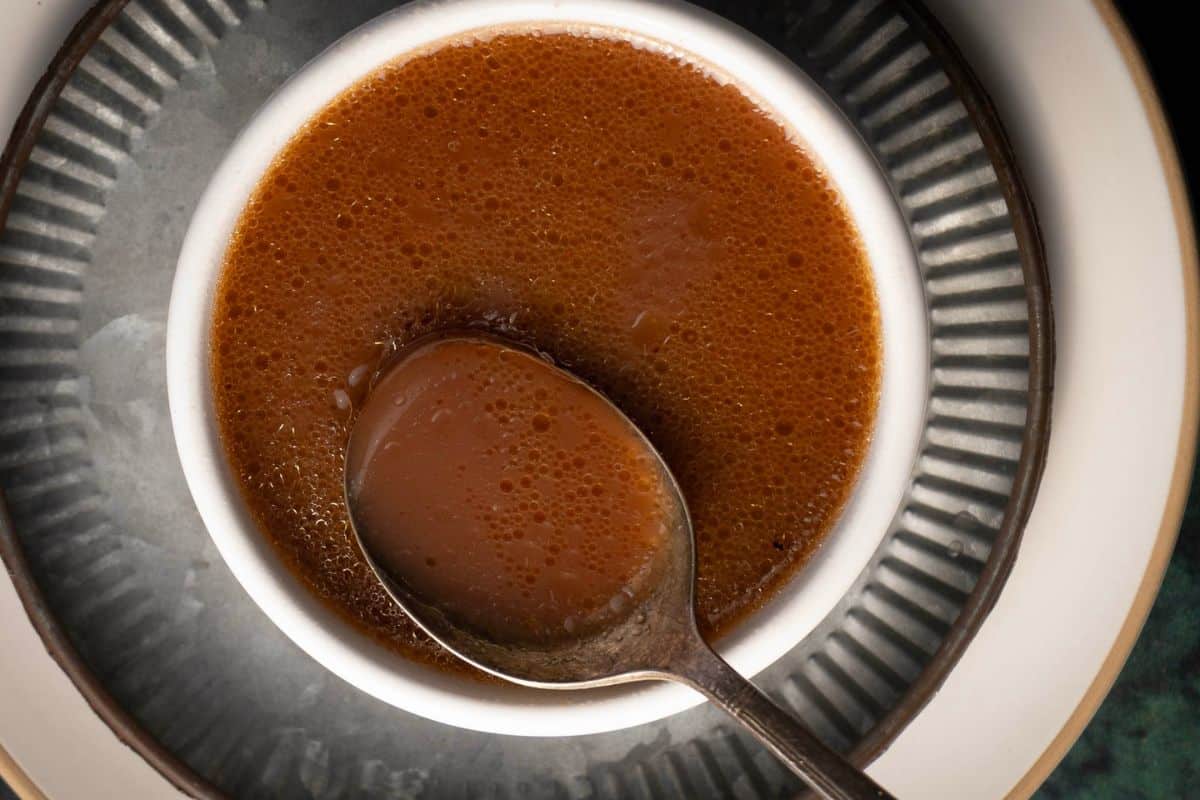 A bowl of chocolate mousse with a spoon resting inside on a patterned plate.