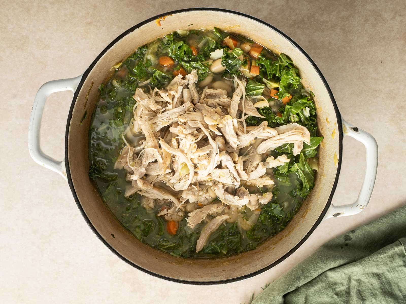 This delightful white bean soup features shredded chicken, hearty kale, and diced carrots, creating a comforting and nutritious meal.