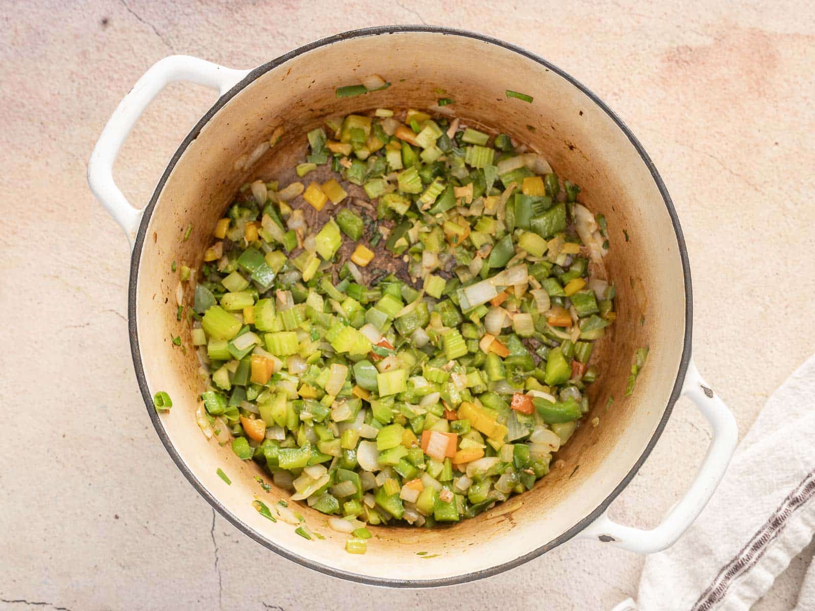 A pot of gluten-free gumbo brimming with a savory mix of chopped vegetables like celery, onions, and carrots sits invitingly on a light-colored surface.
