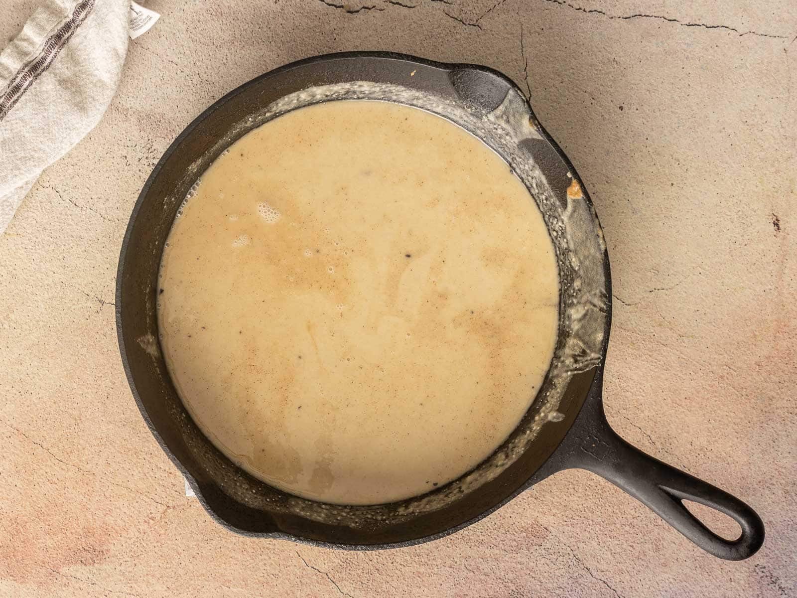 A cast iron skillet filled with creamy gluten-free roux before baking.