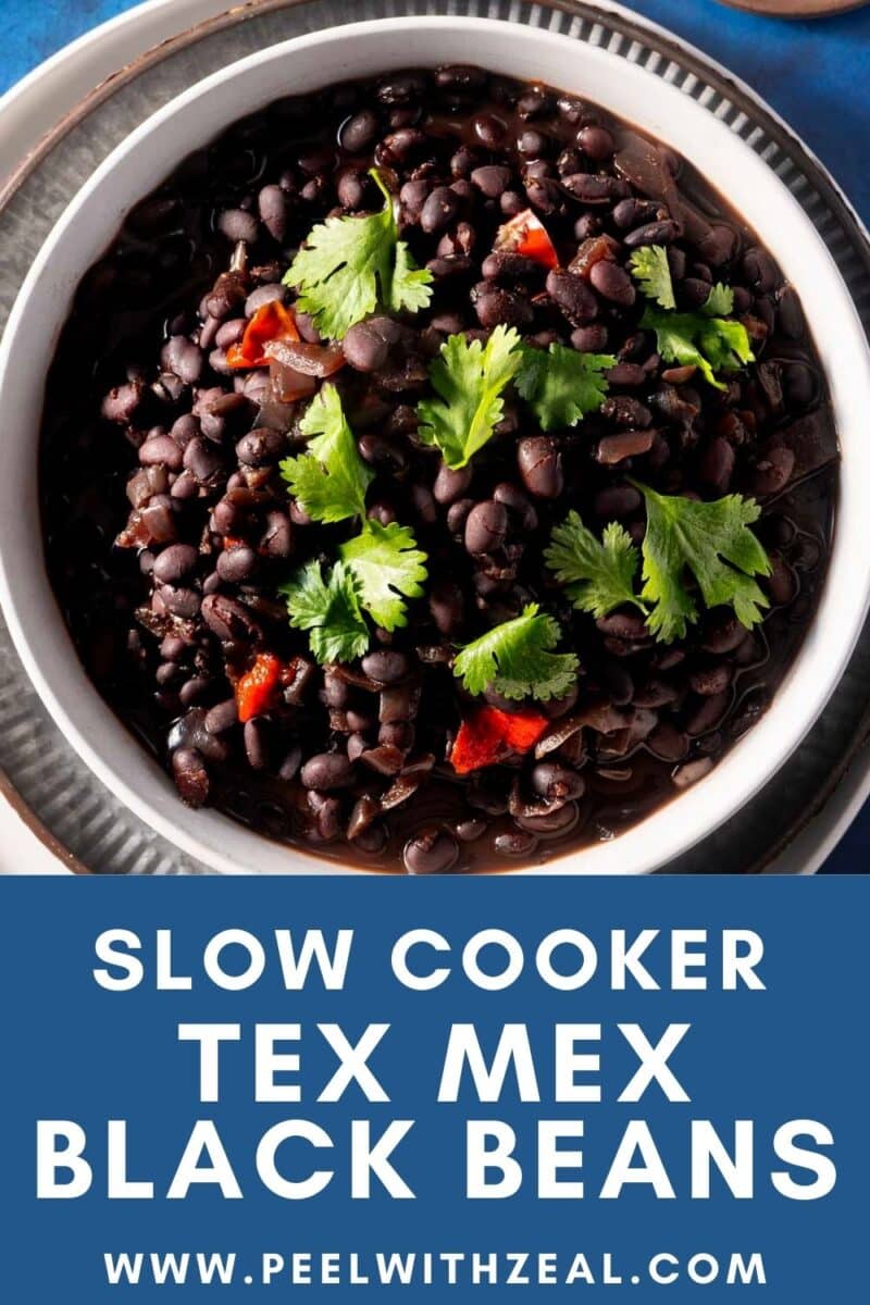 Bowl of cooked black beans garnished with cilantro and red peppers, with text "Slow Cooker Tex Mex Black Beans.