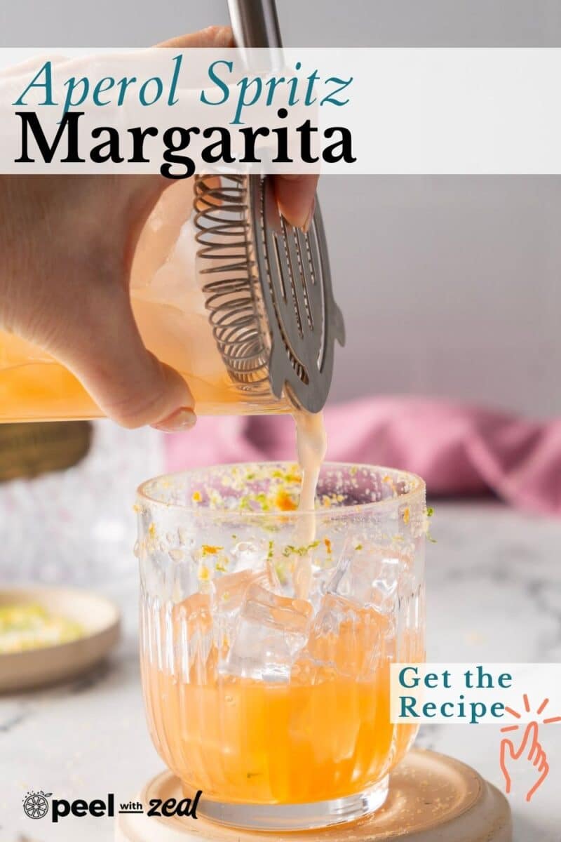 Hand pouring a refreshing Aperol Margarita into an ice-filled glass with a twist of citrus zest; "Get the Recipe" button visible.