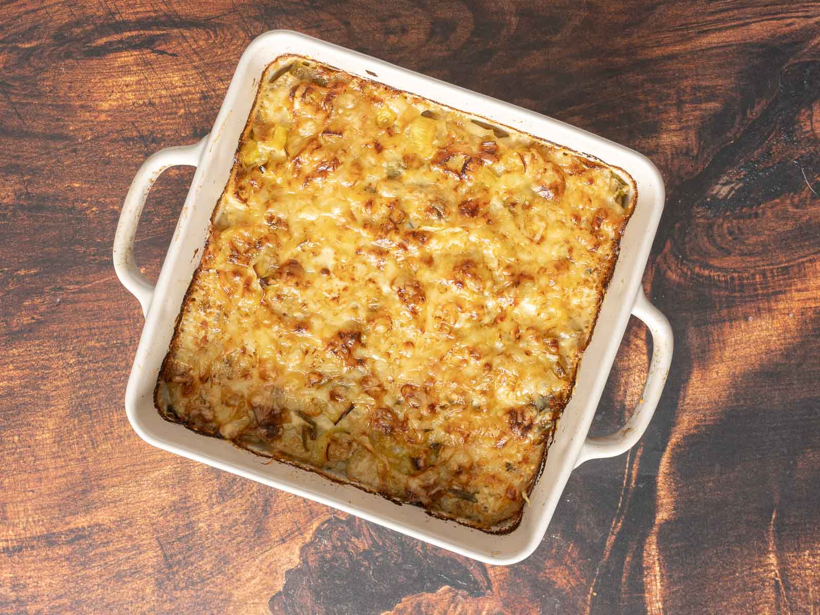 A comforting potato gratin with a golden-brown crust, artfully arranged on a wooden surface.