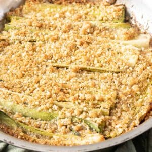 Oven roasted leeks, all covered in a golden breadcrumb topping, nestled perfectly in a round pan.