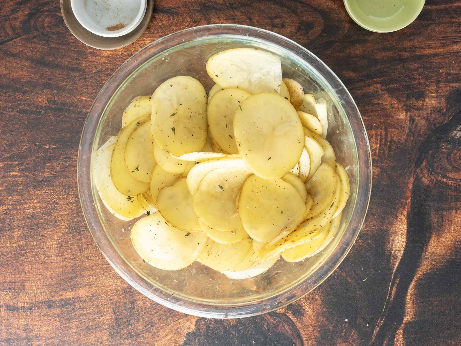 sliced potatoes with herbs and seasonings in a bowl.