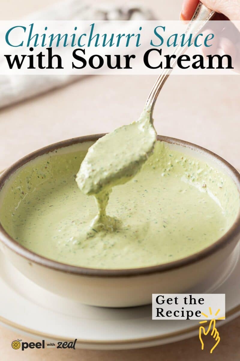 A spoonful of creamy chimichurri sauce swirled with sour cream is held over a bowl, invitingly rich and vibrant.