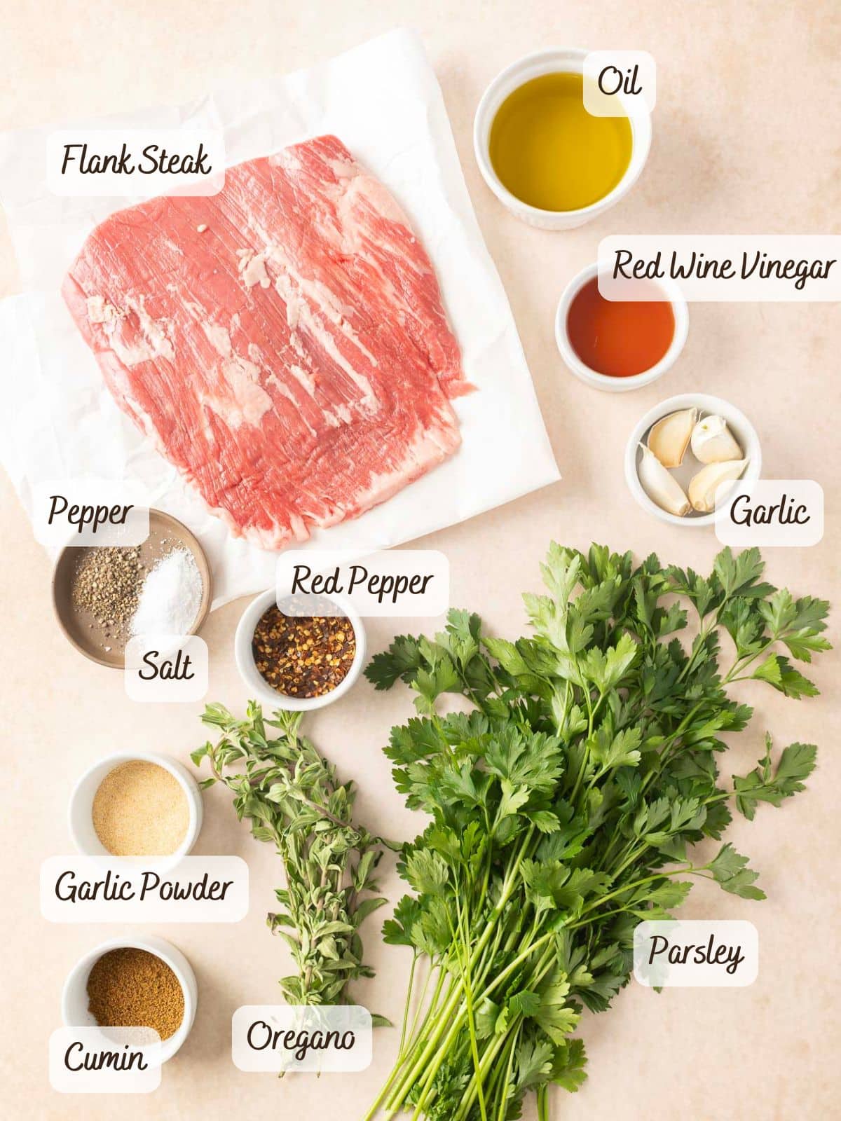 Ingredients for a recipe: flank steak with chimichurri, spices, herbs, oil, garlic, and vinegar arranged on a light surface.