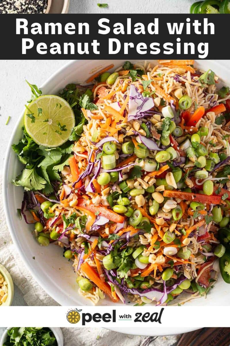 Chilled ramen noodle salad adorned with a zesty peanut dressing, finished with a squeeze of lime and fresh cilantro. This vibrant dish features noodles, crisp red cabbage, edamame, and carrots.