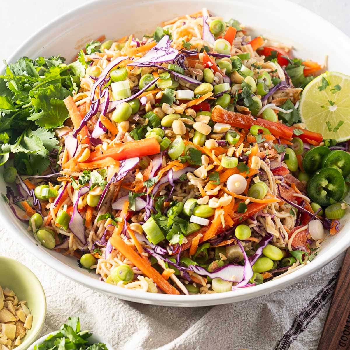 cold ramen noodle salad in a wide white bowl with a slice of lime on the side