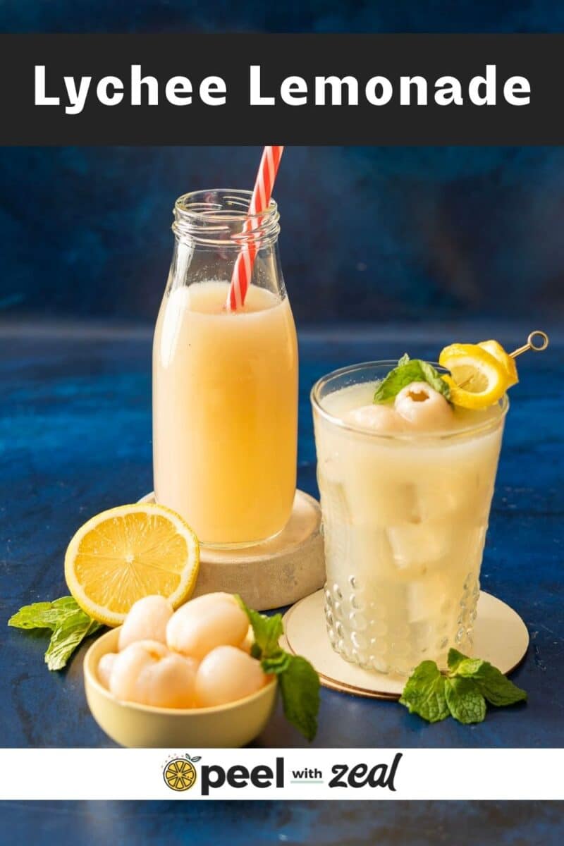Chilled lychee lemonade sparkles in a bottle and glass, adorned with ice, fresh mint, and lemon slices on a vibrant blue surface. A bowl of luscious lychees sits nearby, complementing this refreshing scene.