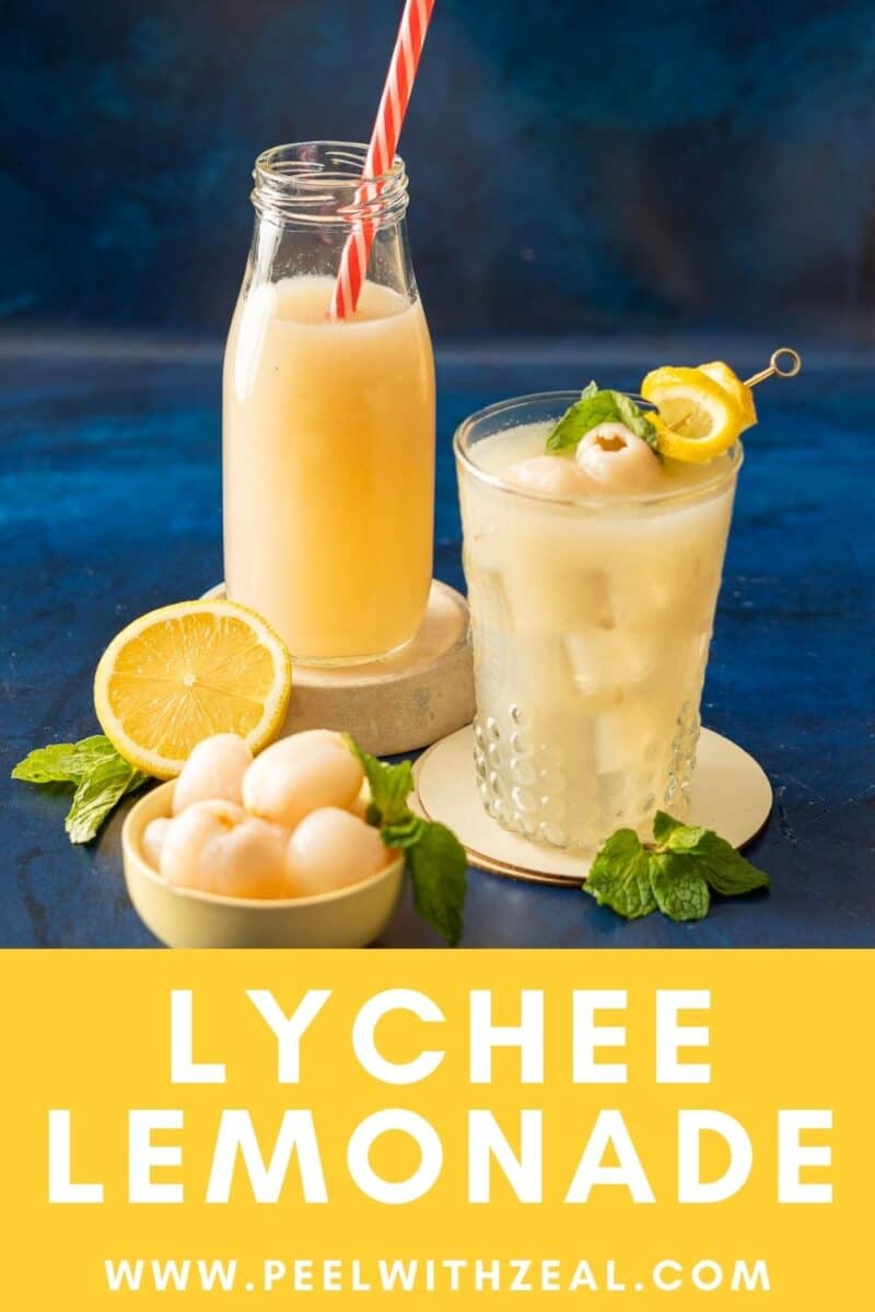 A refreshing glass and bottle of lychee lemonade sit alongside a bowl brimming with lemon slices and lychees, all set against a vibrant blue background.
