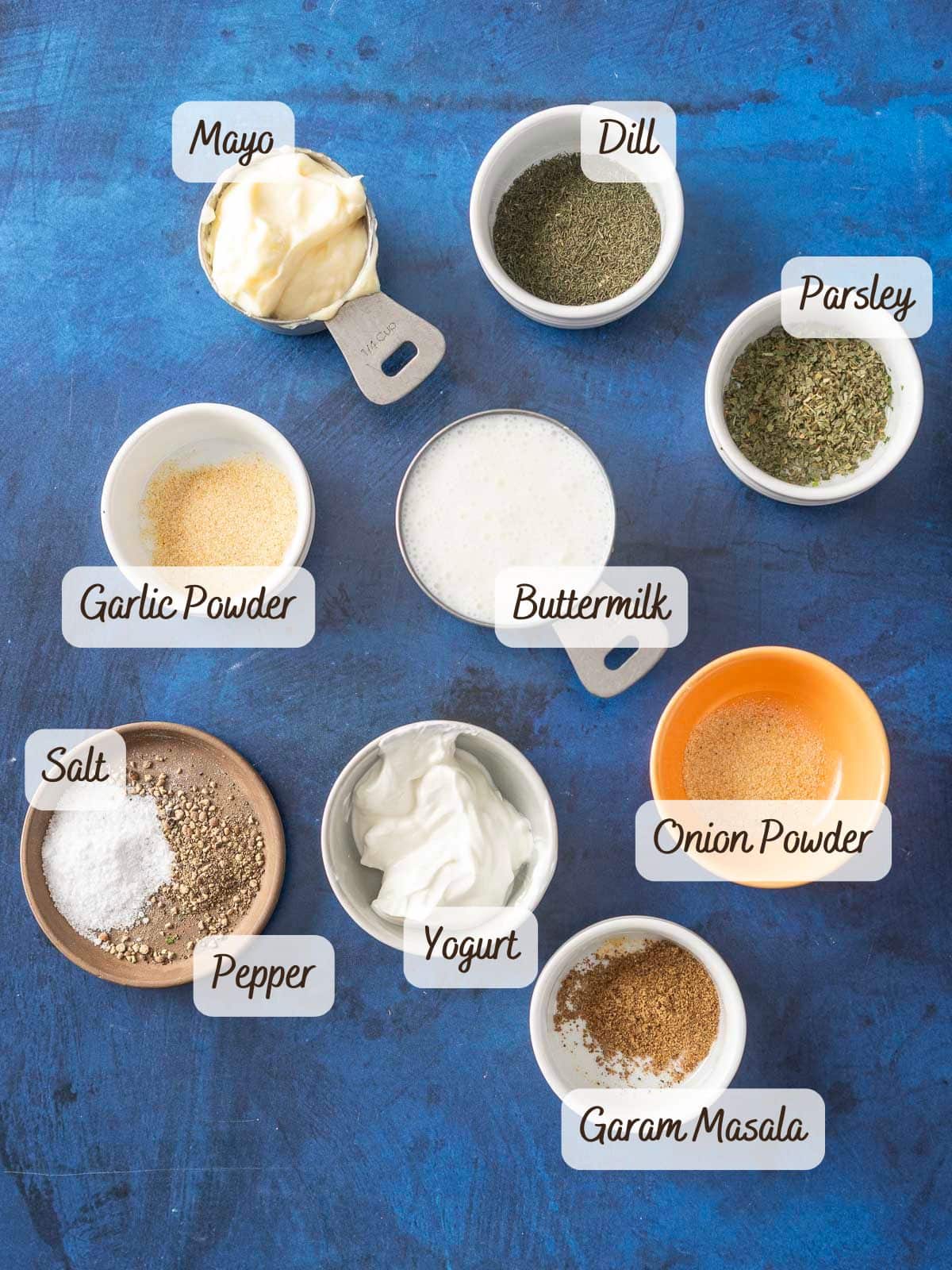 Assorted ingredients in bowls labeled: mayo, dill, parsley, garlic powder, buttermilk, salt, pepper, yogurt, onion powder. 
