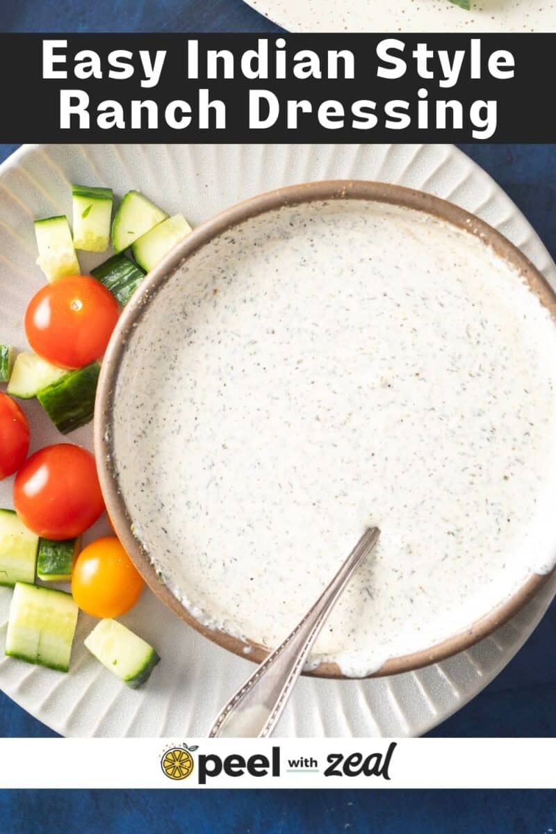A bowl of Indian salad dressing with a spoon, surrounded by fresh cucumber and tomatoes on a plate.