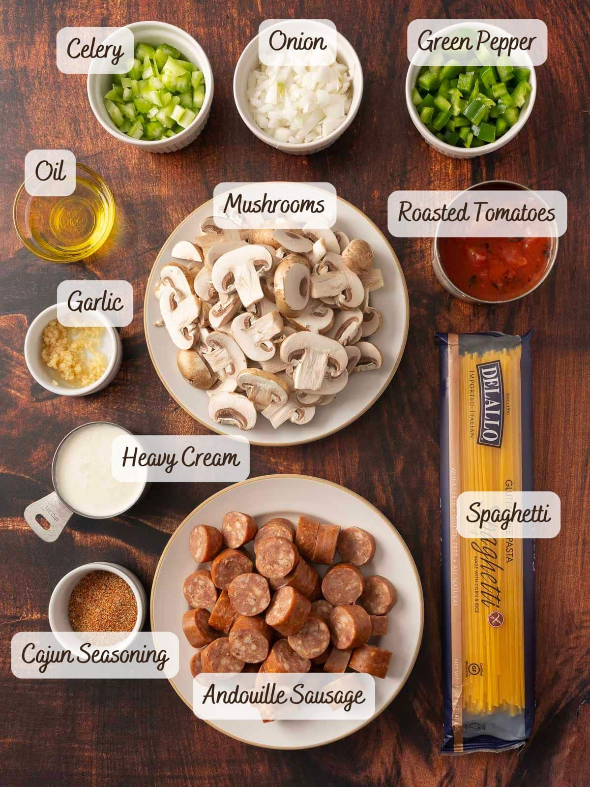 A vibrant array of ingredients for a Cajun sausage spaghetti dish is spread across the table: celery, onion, green pepper, oil, garlic, mushrooms, tomatoes, cream, and a hint of seasoning to elevate your culinary creation.