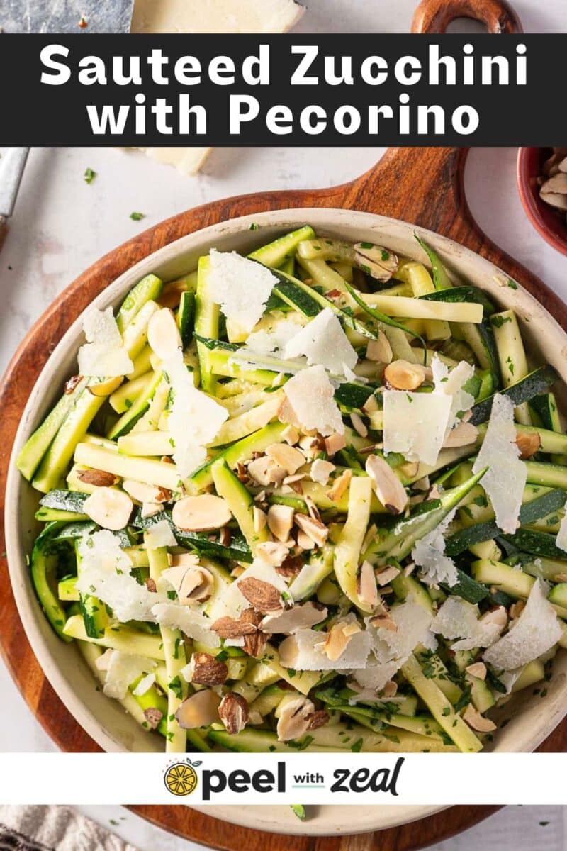 A bowl of perfectly sautéed zucchini garnished with sliced almonds and pecorino cheese. Elegantly presented on a round wooden board adorned with a stylish logo at the base.