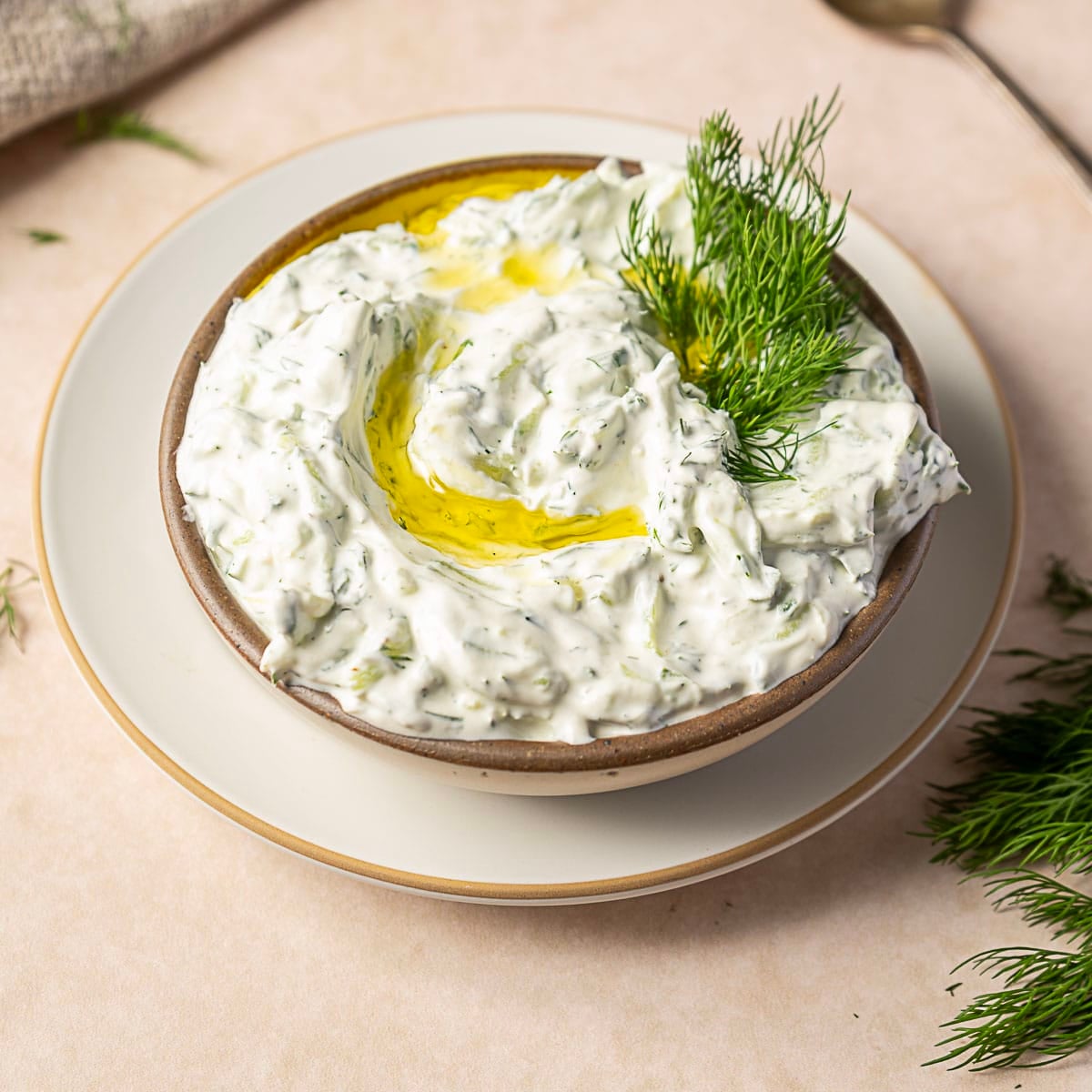 tzatziki sauce with sour cream in a bowl that's on top of a plate