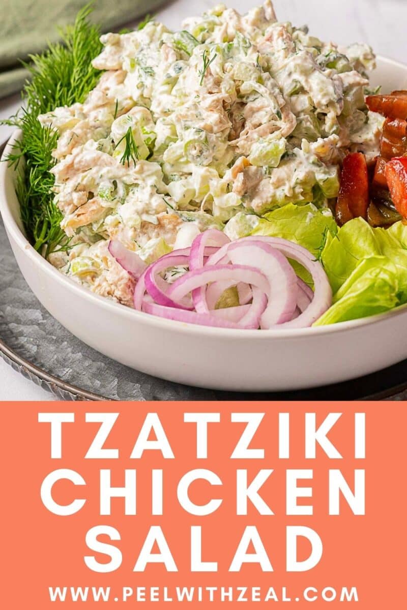 A bowl of tzatziki chicken salad with fresh dill, lettuce, tomato, and sliced red onion.