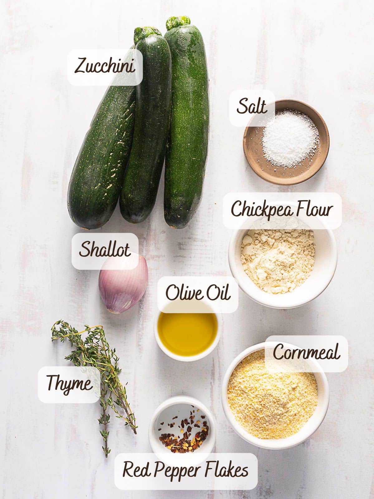 Scarpaccia: Zucchini, salt, chickpea flour, shallot, olive oil, cornmeal, thyme, and red pepper flakes elegantly arranged on a light surface.