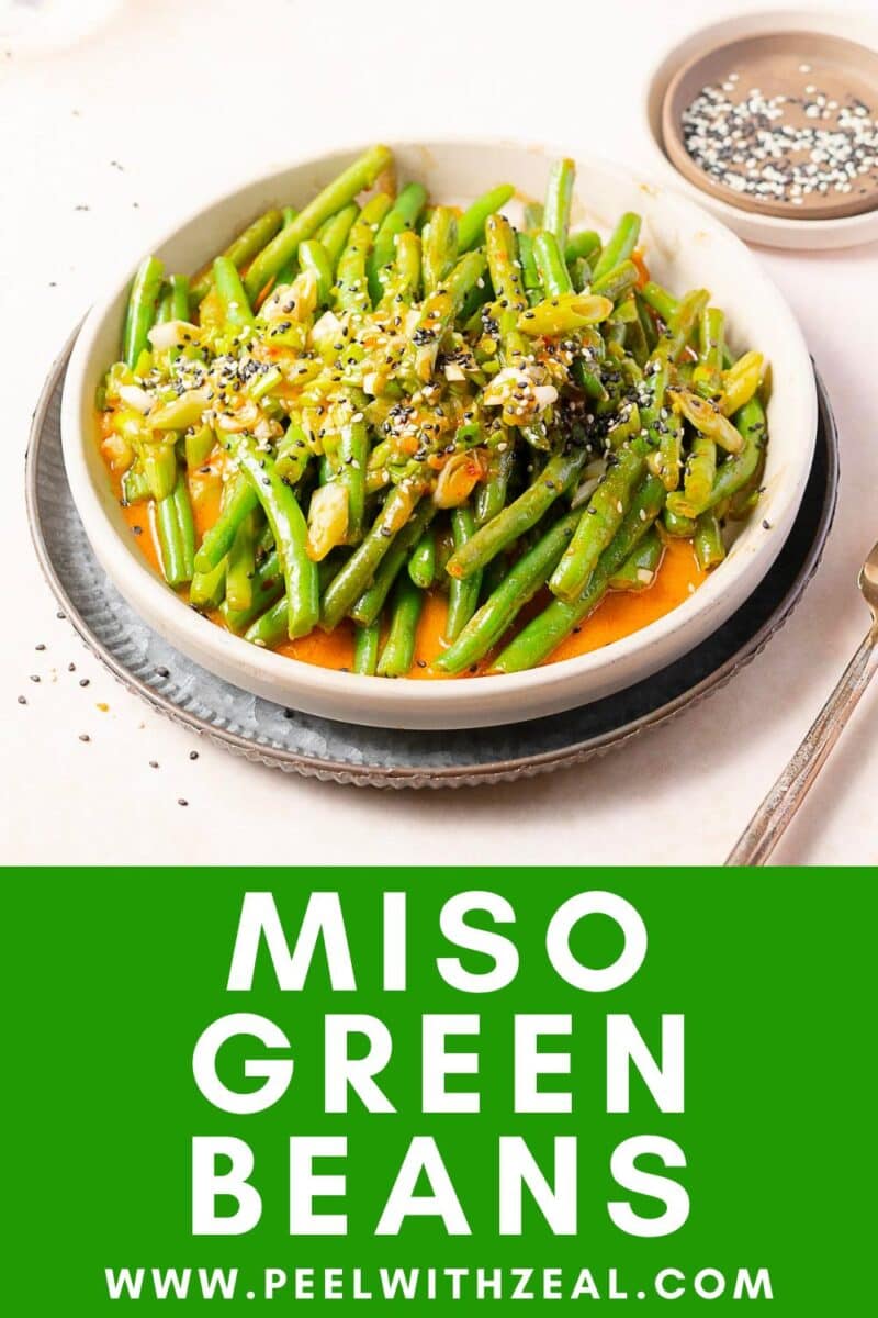 A bowl of miso green beans topped with sesame seeds and sauce, placed on a plate with a fork beside it; text reads "Miso Green Beans" and "www.peelwithzeal.com".