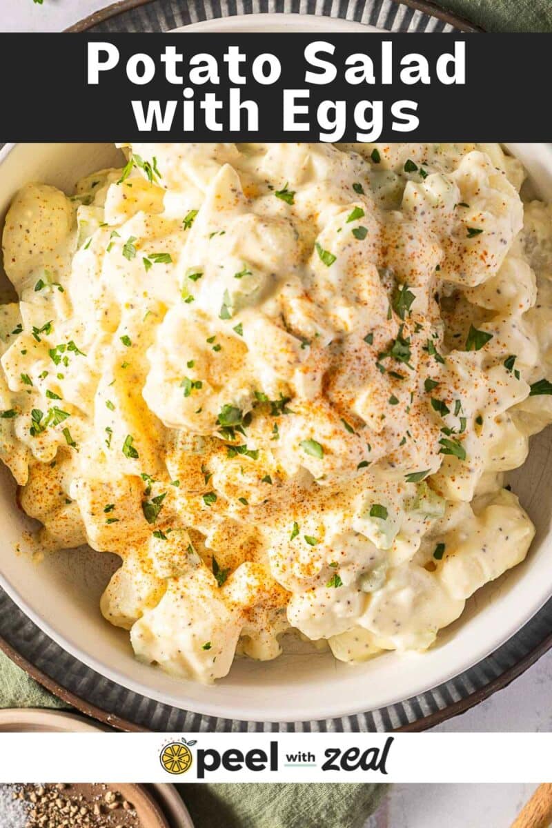 A bowl of old-fashioned potato salad with eggs, sprinkled with paprika and garnished with parsley.
