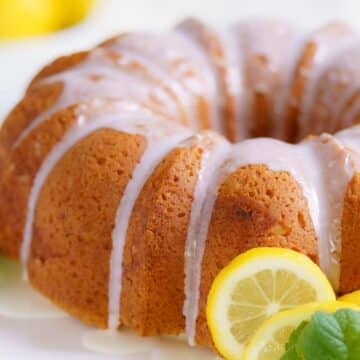 A delightful bundt cake with a white glaze drizzled on top, garnished with lemon slices and mint leaves. Perfect for gluten-free Easter desserts, it's a charming centerpiece for your holiday table.