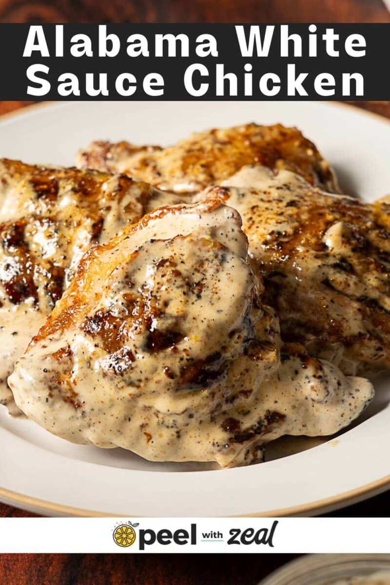 Close-up of grilled alabama chicken pieces covered in a creamy white sauce on a plate, with the text "Alabama White Sauce Chicken" at the top.