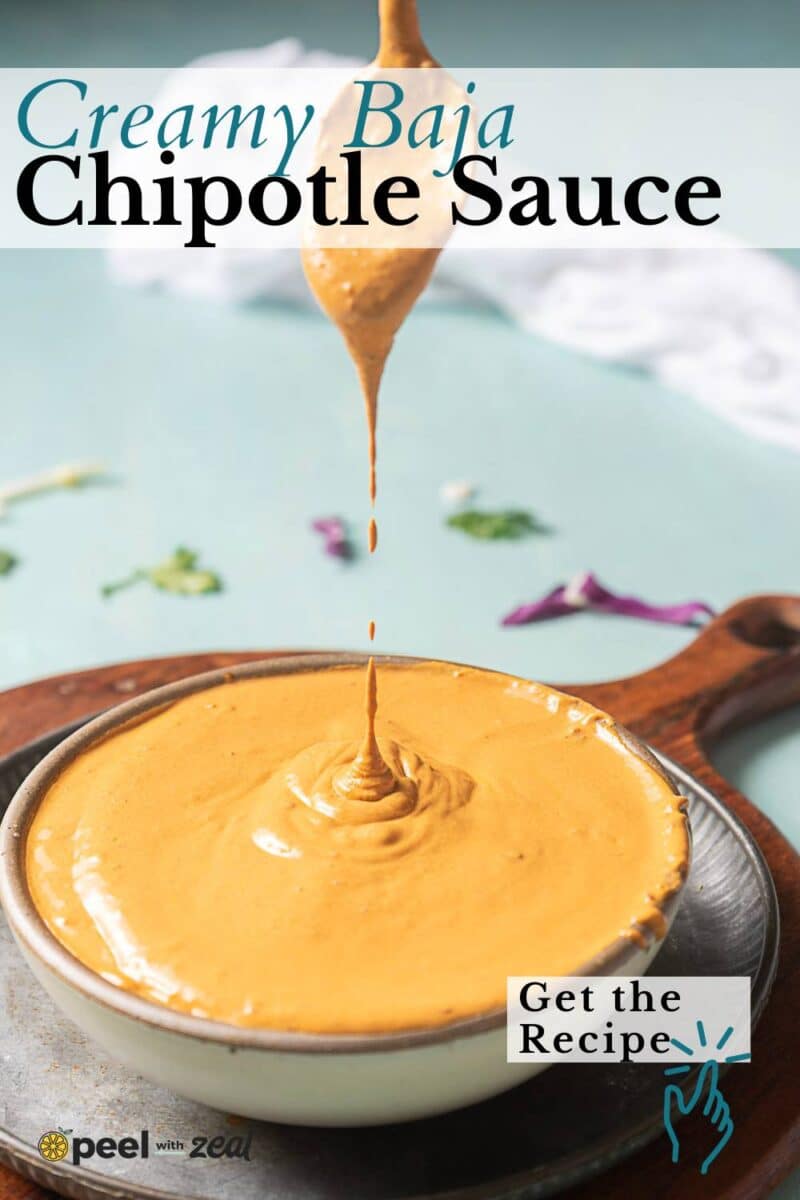 A bowl of creamy chipotle sauce with sauce dripping from a spoon above it, set on a wooden board with a "Get the Recipe" label.