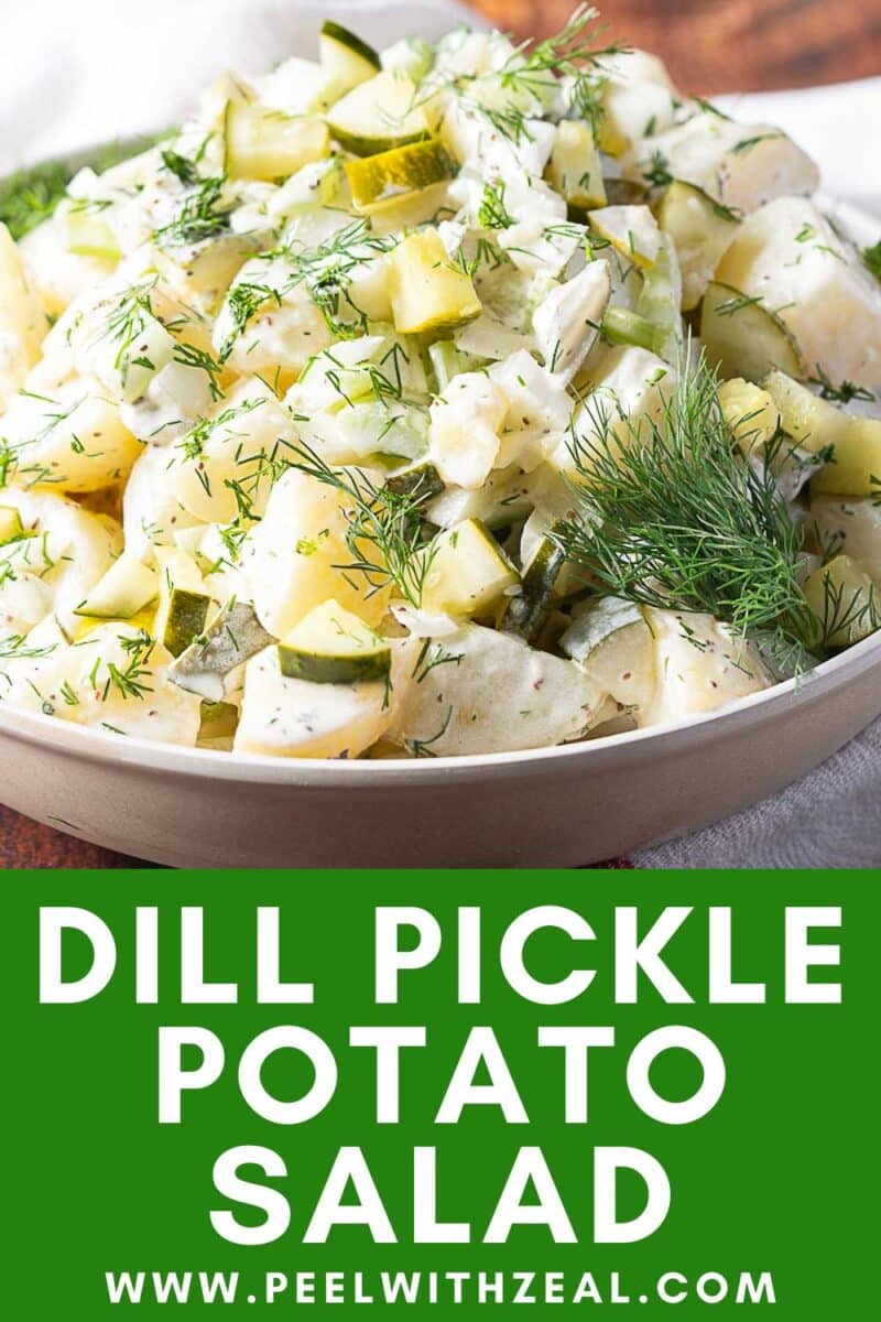 A bowl of potato salad with dill pickles, garnished with fresh dill, sits on a white cloth.