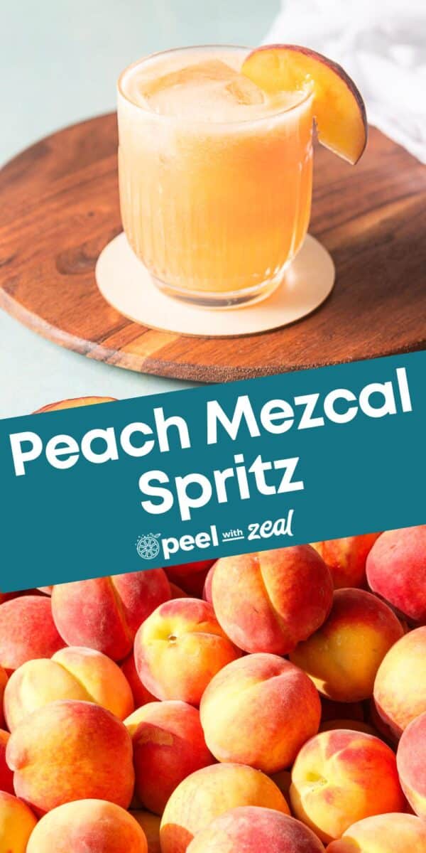 A glass of peach mezcal spritz with a peach slice garnish sits on a wooden surface above a pile of fresh peaches