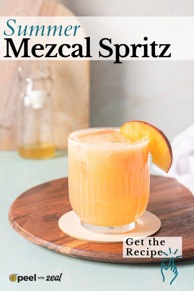 A peach-colored mezcal spritz garnished with a peach slice sits on a wooden board with a bottle and towel in the background. Text reads "Summer Mezcal Spritz" and "Get the Recipe.