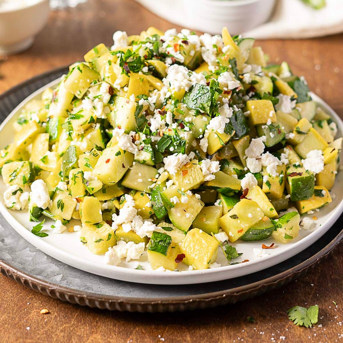 sauteed zucchini and squash with feta on a white plate